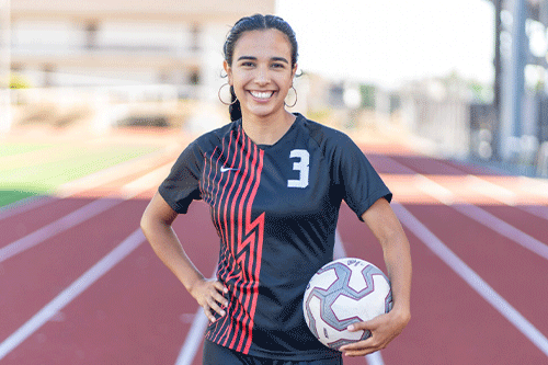 Elizabeth Martinez poses with soccer gear on the EvCC track.