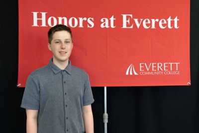 Kai Decker stands in front of red Honors at Everett banner