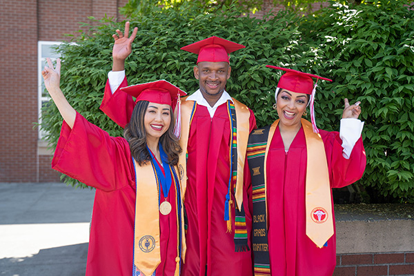 Mailee Nguyen (left) with two friends at EvCC commencement ceremony wearing caps and gowns