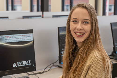 Natalie VanWinkle sitting next to a computer in the Learning Resource Center's computer lab. 