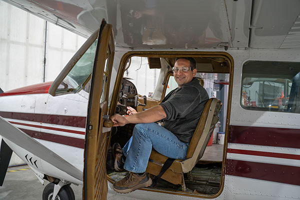 EvCC Aviation student Shad Fleshman-Cooper sits in cockpit of aircraft in the Aviation Maintenance Technician school's hangar.