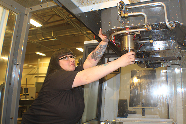 Leeann Riggs works with a large machine.