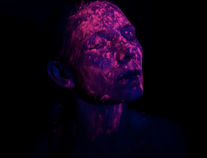 Julia Goodridge- photographic portrait of a person with neon paint splattered on their face.