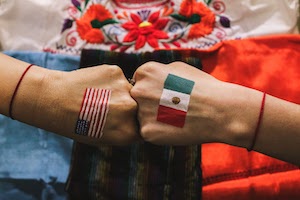 Reyna Davalos- photo of two fists bumped together with an american flag and a mexican flag painted on the back.