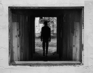 Keegan Baker- black and white photograph of a black silhouette at the end of a small hallway.