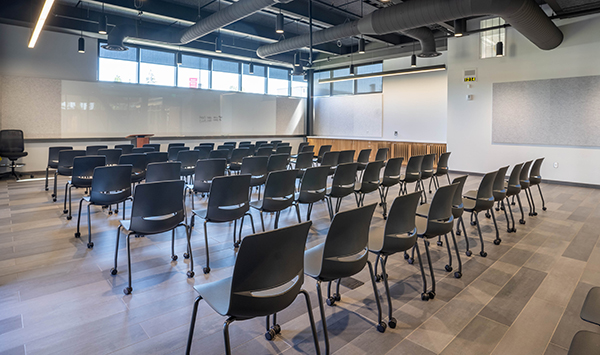 The summit room has a shiny whiteboard at the front, chair set up for a presentation and a high ceiling with windows.